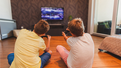Two Boys Playing Games sitting on the floor in front of TV