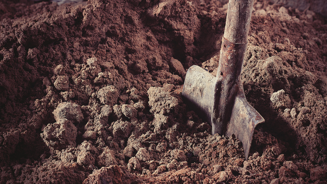 Old rusty shovel in sand on building.