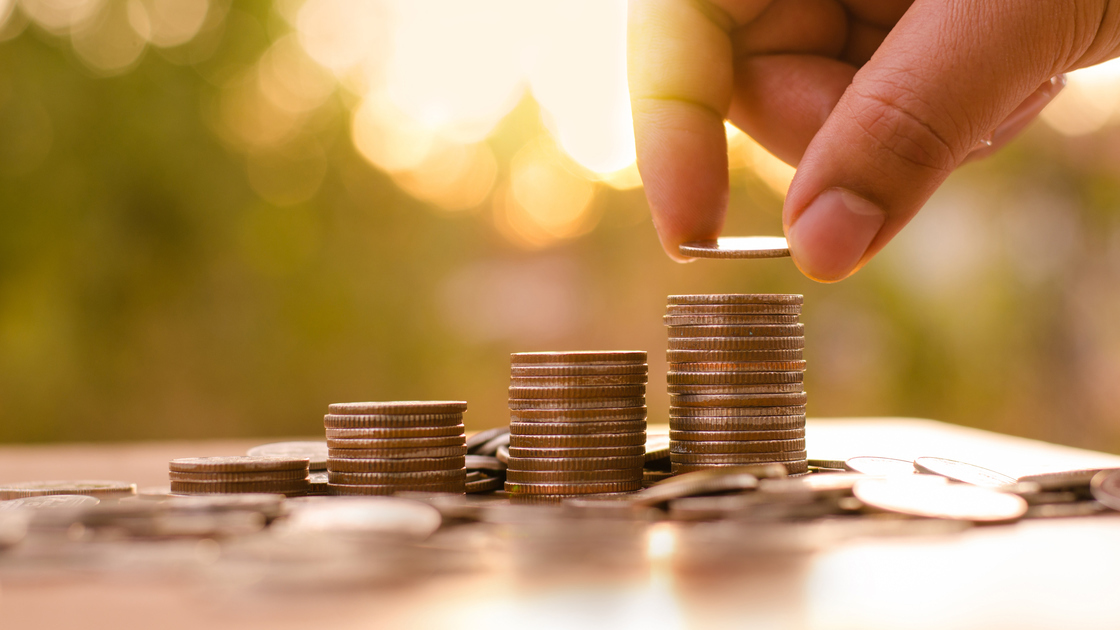 business man putting money coins like growing graph with sun light in saving money and investor insurance concept over green background