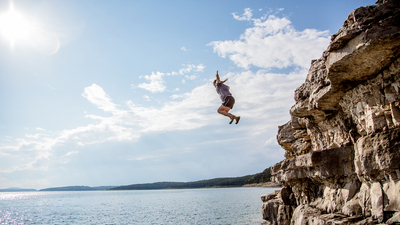 A group of friends jump from cliffs into the lake.