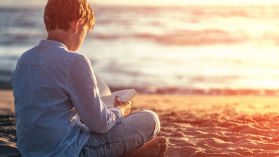 Reading a book on the beach at sunset