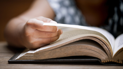 Closeup child hand opening and reading a book in library in vintage color tone