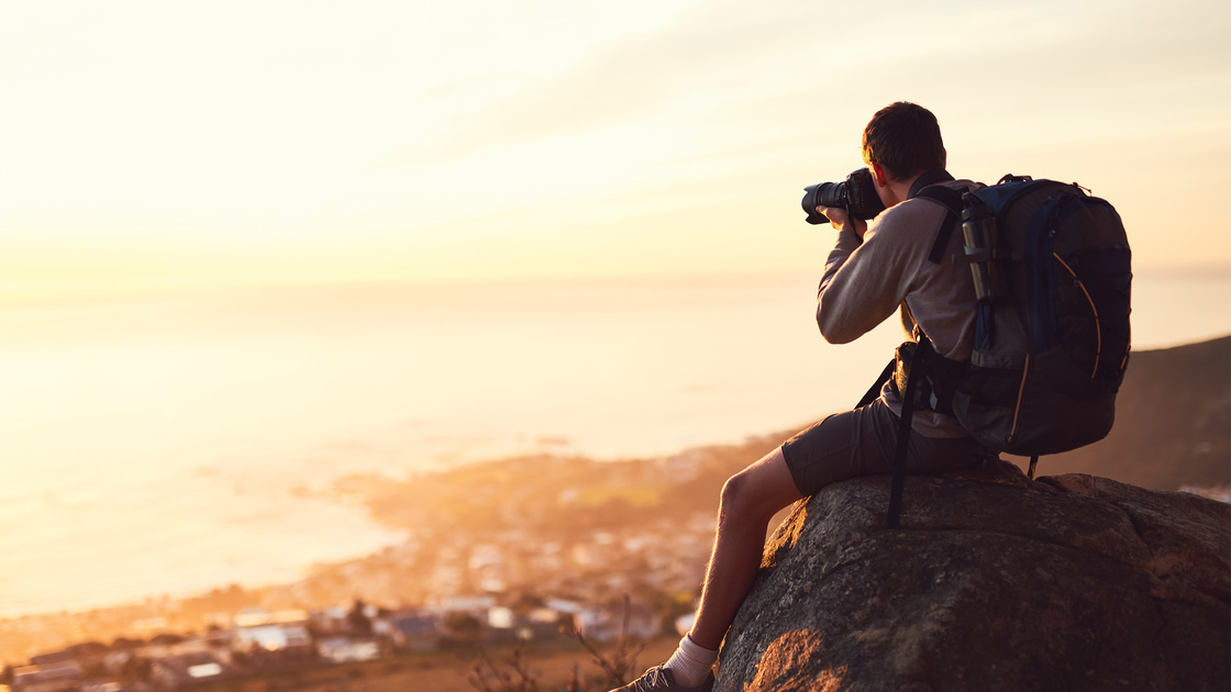 Shot of a young photographer taking a picture from the top of a mountain