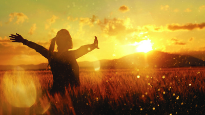 silhouette in the sunset, young woman with her arms raised enjoying summer twilight in the middle of nature.