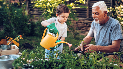 Grandfather and grandson playing in backyard with gardening tools