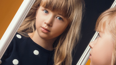 child in the Studio posing in fashionable clothes to looks in a mirror