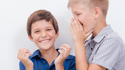 Teenage boy whispering  a secret in the ear of surprised  friend on white  background