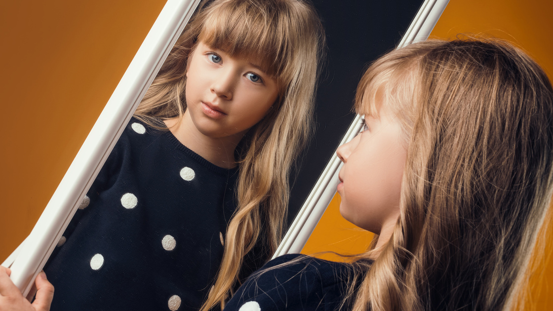 child in the Studio posing in fashionable clothes to looks in a mirror