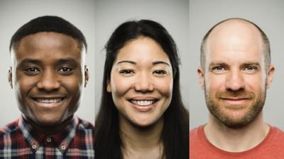 Close-up portrait of man smiling. Happy male is against gray background. He is wearing plaid shirt. Vertical studio photography from a DSLR camera. Sharp focus on eyes.