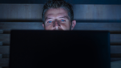 young attractive and relaxed internet addict man networking concentrated late at night on bed with laptop computer in social media addiction or workaholic businessman concept