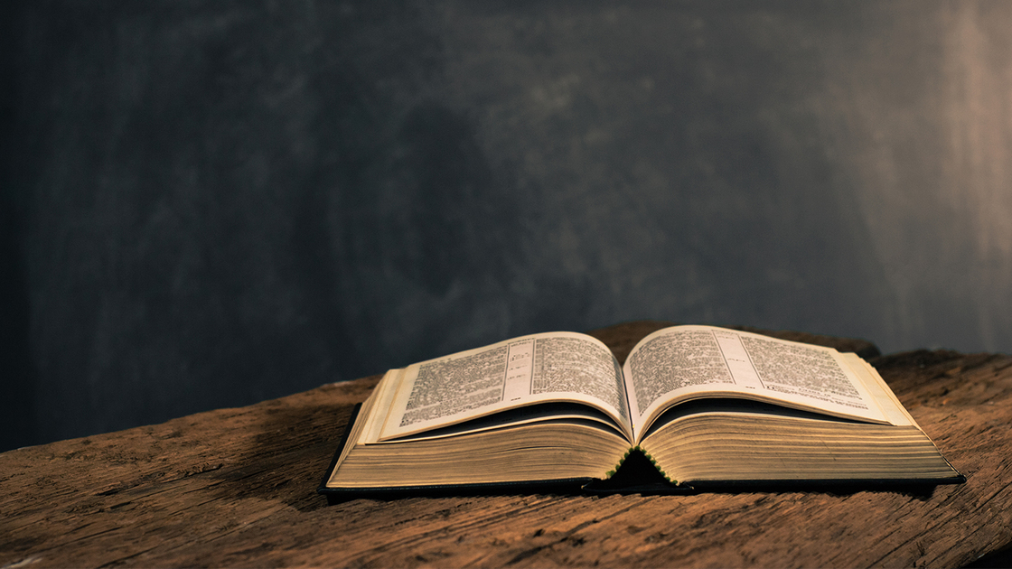 Bible on a old oak wooden table. Beautiful dark background. Religion concept