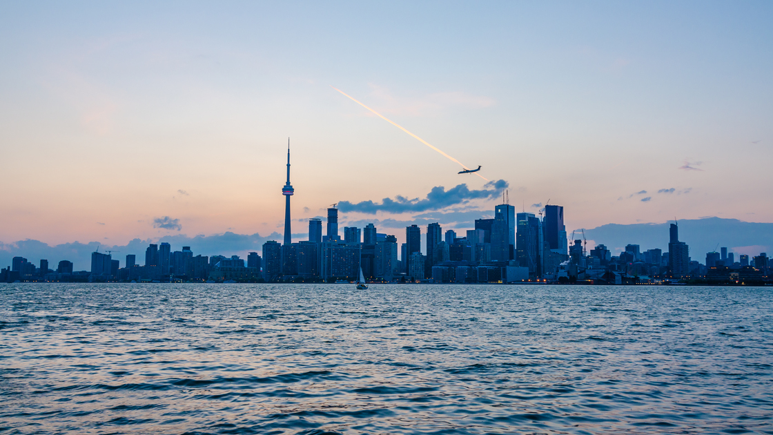 Skyline of Toronto over Ontario Lake at sunset with sail boat