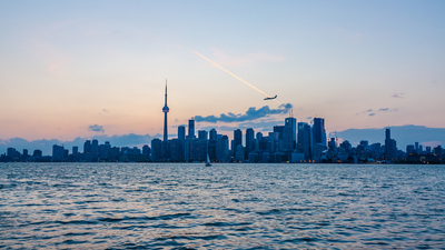 Skyline of Toronto over Ontario Lake at sunset with sail boat