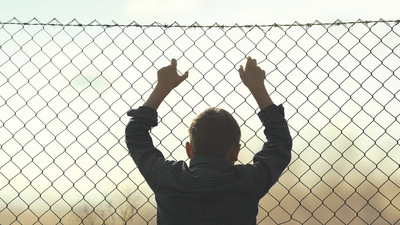 young boy looks out from the net towards freedom