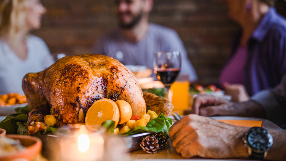 Close up of stuffed roasted turkey during family's dinner at dining table.