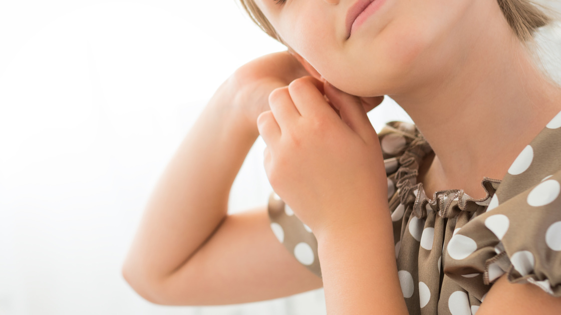 7 or 8 years old little girl with blond hair posing pointing with earrings