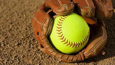 A new  fluorescent yelllow softball in glove sitting in the dirt