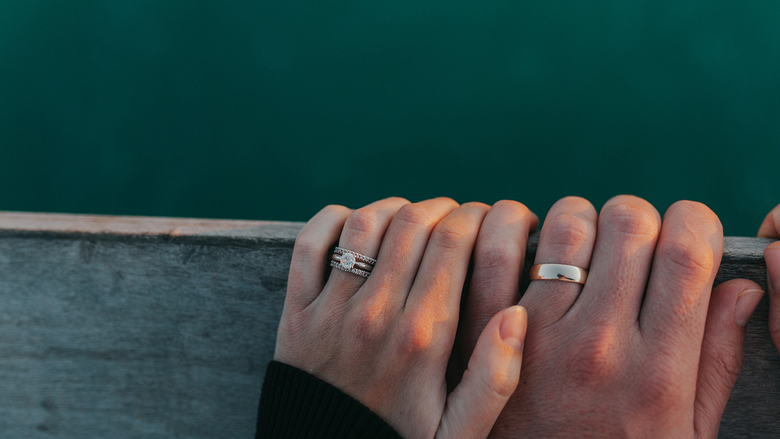 A married couple hold hands on a pier railing above the beautiful Gulf of Mexico.
