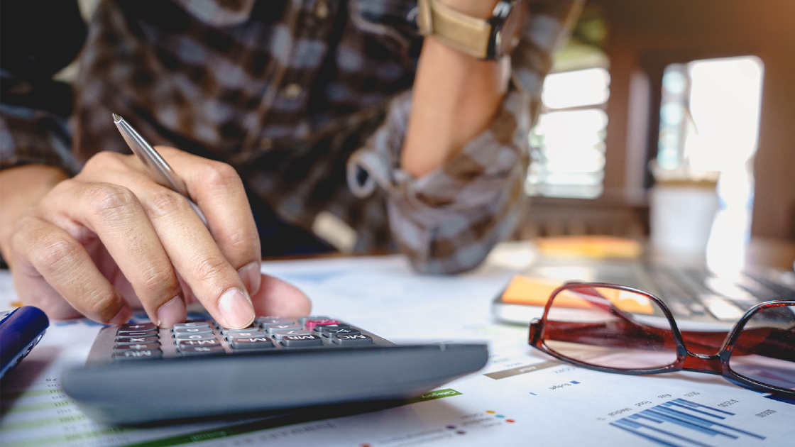 Close up of businessman or accountant working on calculator to calculate business data, and accountancy document. Business financial and accounting concept