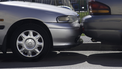 Hitting into a parked car while parking a vehicle in a parallel line parking space. 