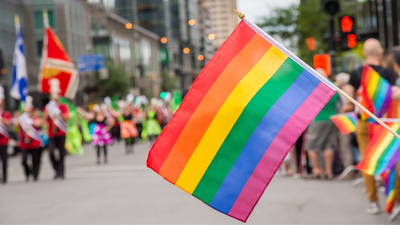 Gay rainbow flags at Montreal gay pride parade with blurred spectators in the background