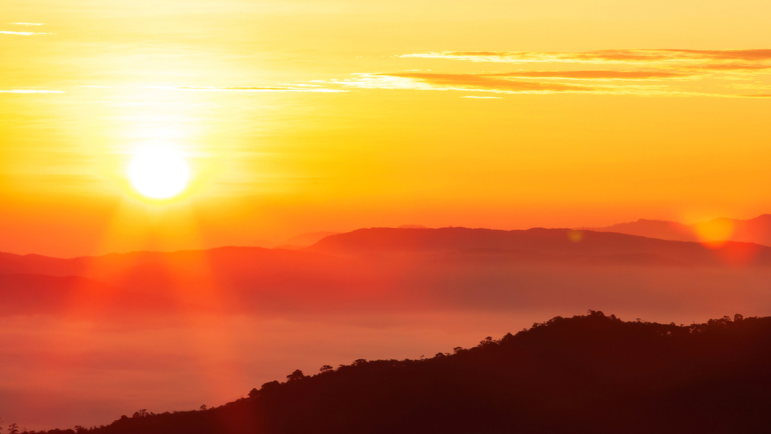 Glowing sunrise shines over mountain range, magical star shape ray from the sun with lens flare. Exploration, inspiration concept.