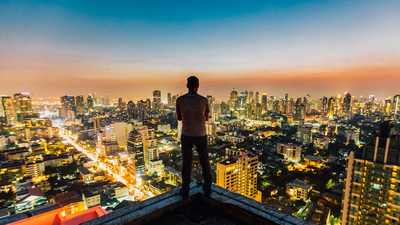 man standing on top of a skyscraper view of the Bangkok city skyline.