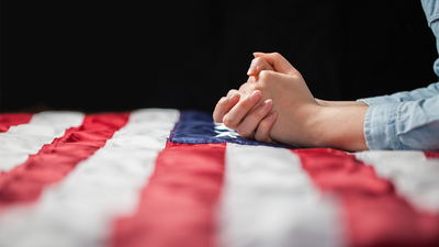 Hands praying over american flag