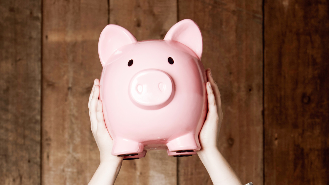 Young boy in retro clothing holding up his piggybank