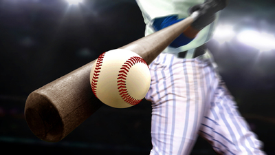 Baseball player swing hitting ball with bat in close up under stadium spotlights