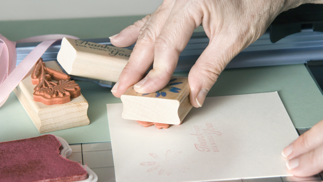 Closeup of a senior woman making homemade greeting cards with stamps and cardstock.