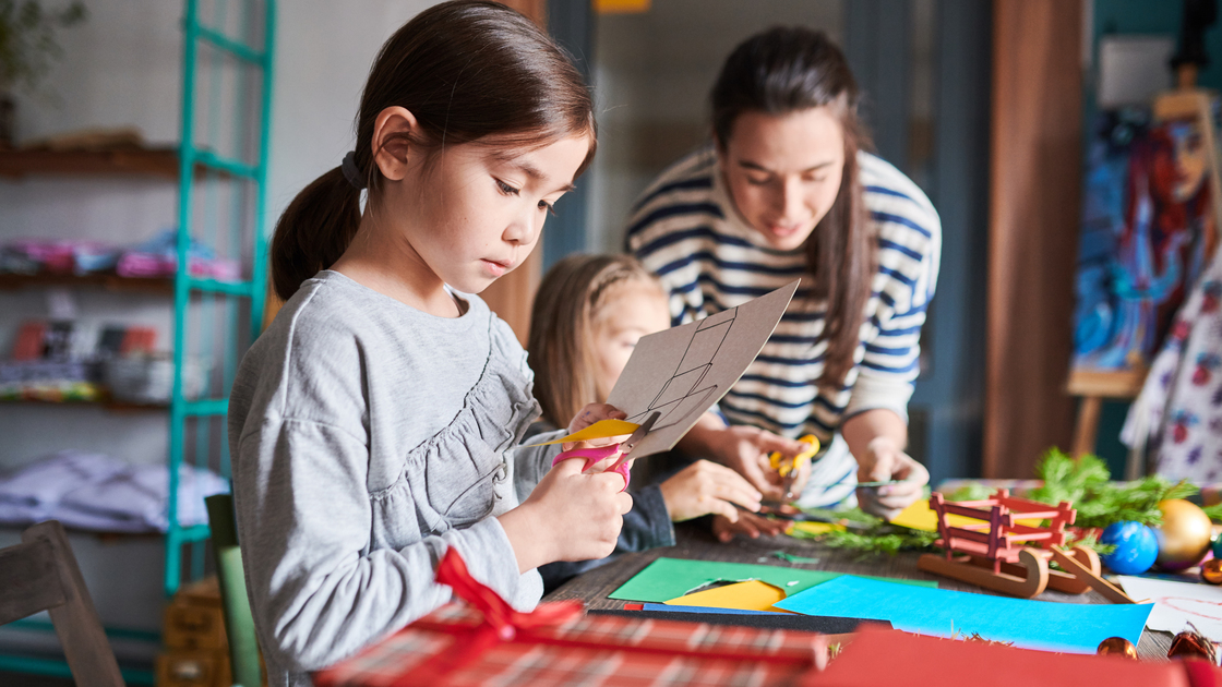 Side view portrait of cute Asian girl making handmade Christmas gifts in art and craft class, copy space