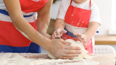 Mother and her cute daughter hands prepares the dough on wooden table. Homemade pastry for bread or pizza. Bakery background.