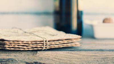 Pack of matzah or matza and red kosher wine on a vintage wood background. Jewish Passover holiday composition