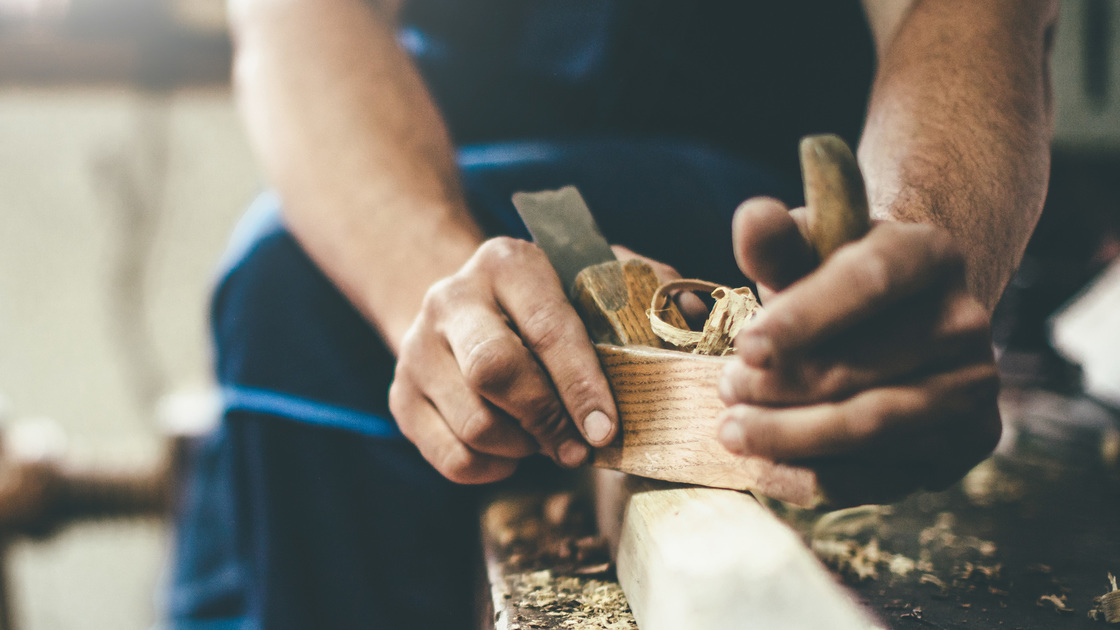 carpenter working with planer at the workshop. closeup view of carpenter's hands