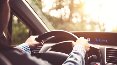 Woman driving car at sunny.