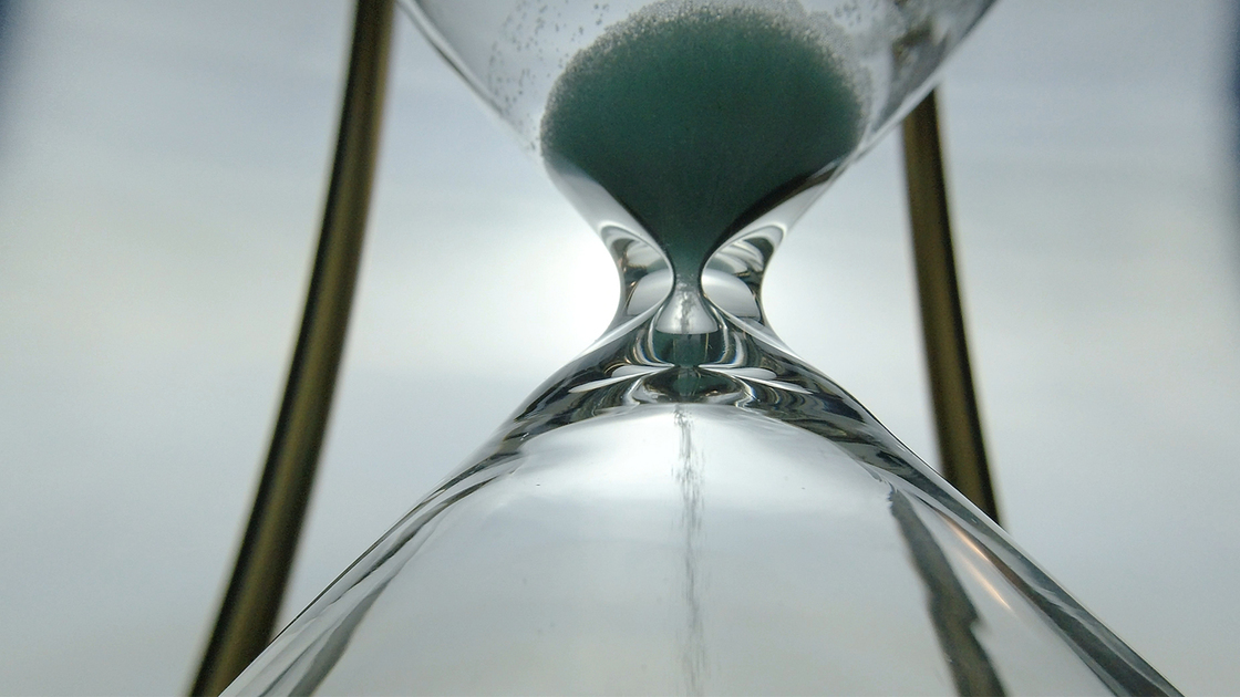 Extreme close up view of sand flowing through an hour glass. Super closeup of hourglass clock middle.  Classic sandglass timer countdown.
