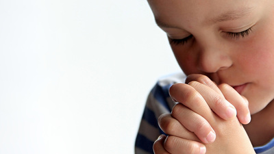 boy praying to God stock image with hands held together with closed eyes stock photo