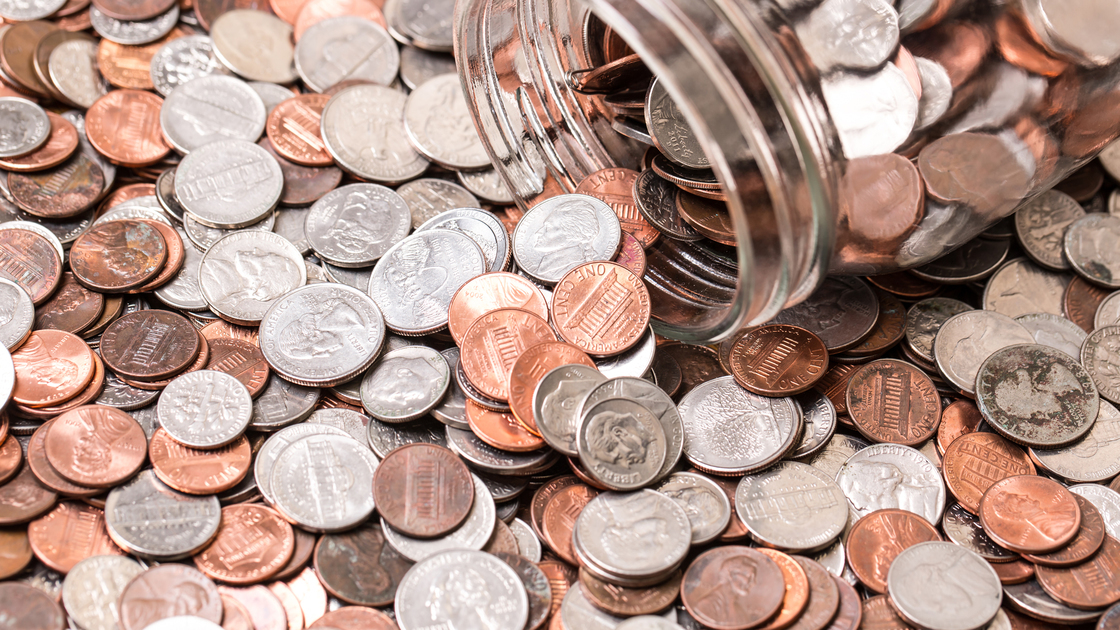 Close up of many different type of coins with jar