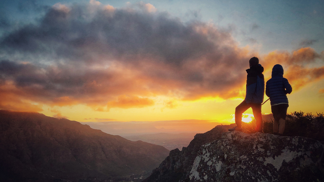 Silhouette of two boys on a mountain top at sunset above Jonkershoek Stellenbosch South Africa