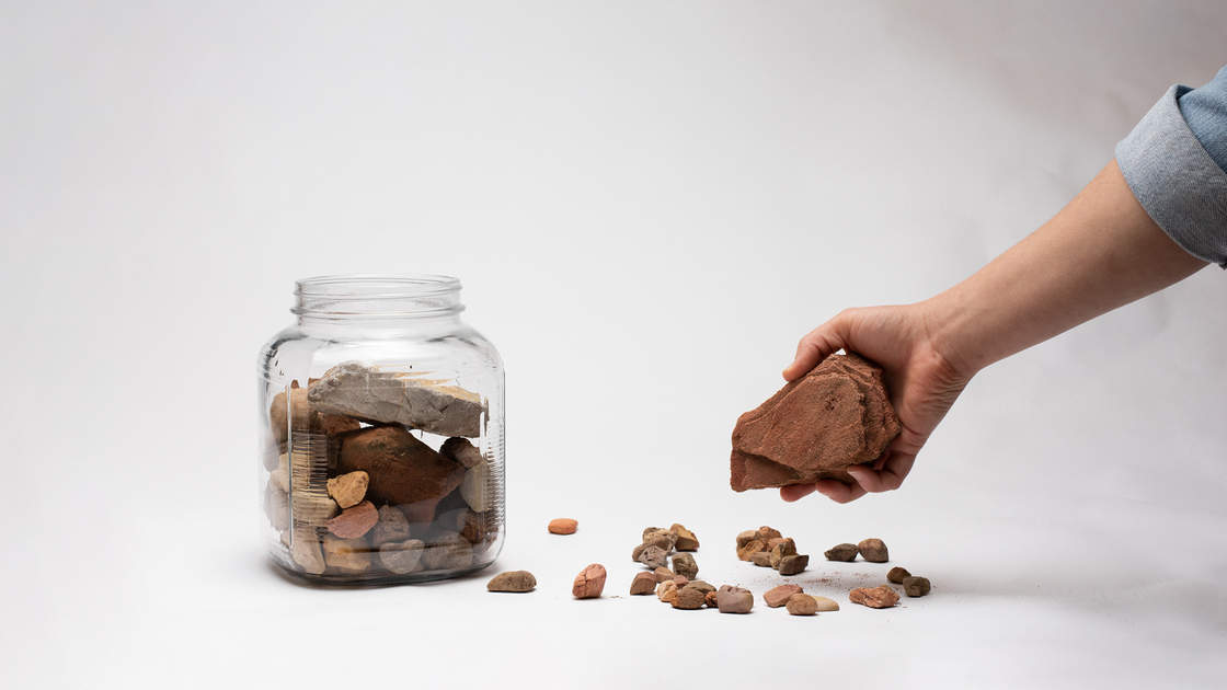 Hand putting rocks in a large jar