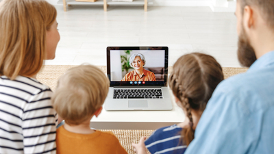 From above young parents and children resting   using laptop to speak with senior woman at home