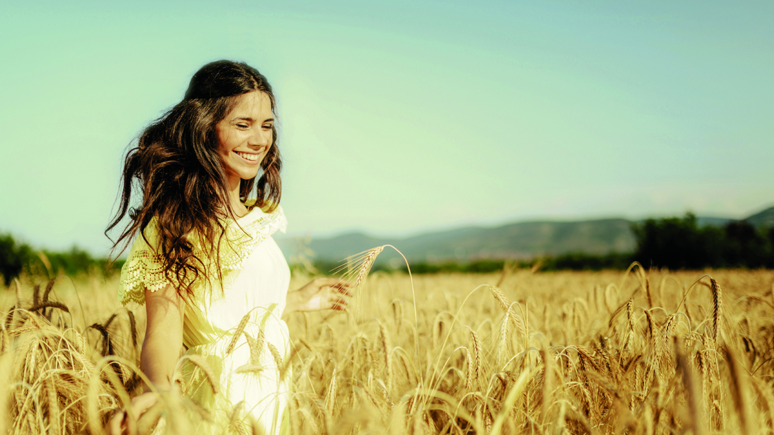 beautiful young woman in a wheat golden field on sunny summer day