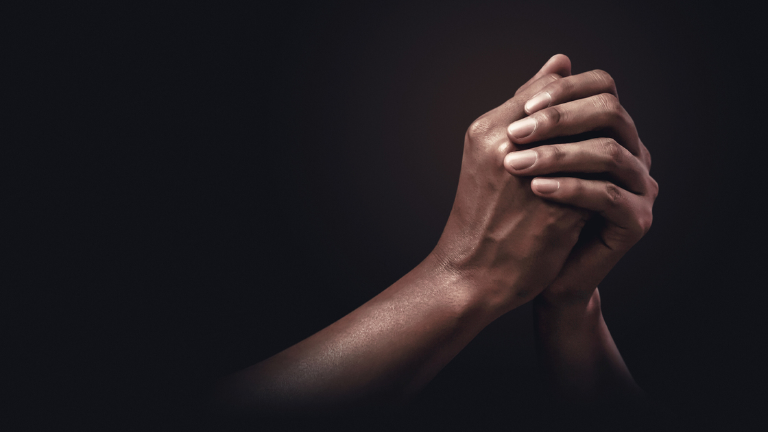 Praying hands with faith in religion and belief in God on dark background. Power of hope or love and devotion.