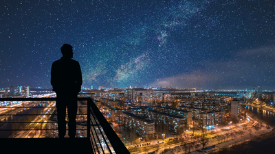 The man standing on the top of building on the starry cityscape background