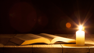 bible on the table in the light of a candle