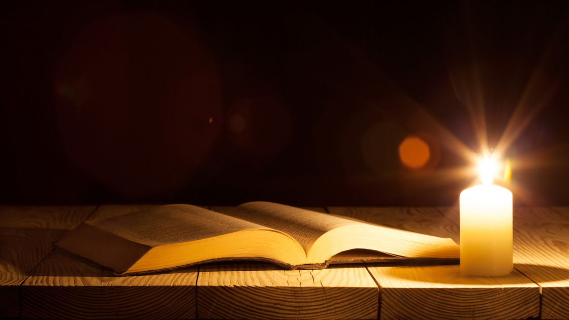 bible on the table in the light of a candle