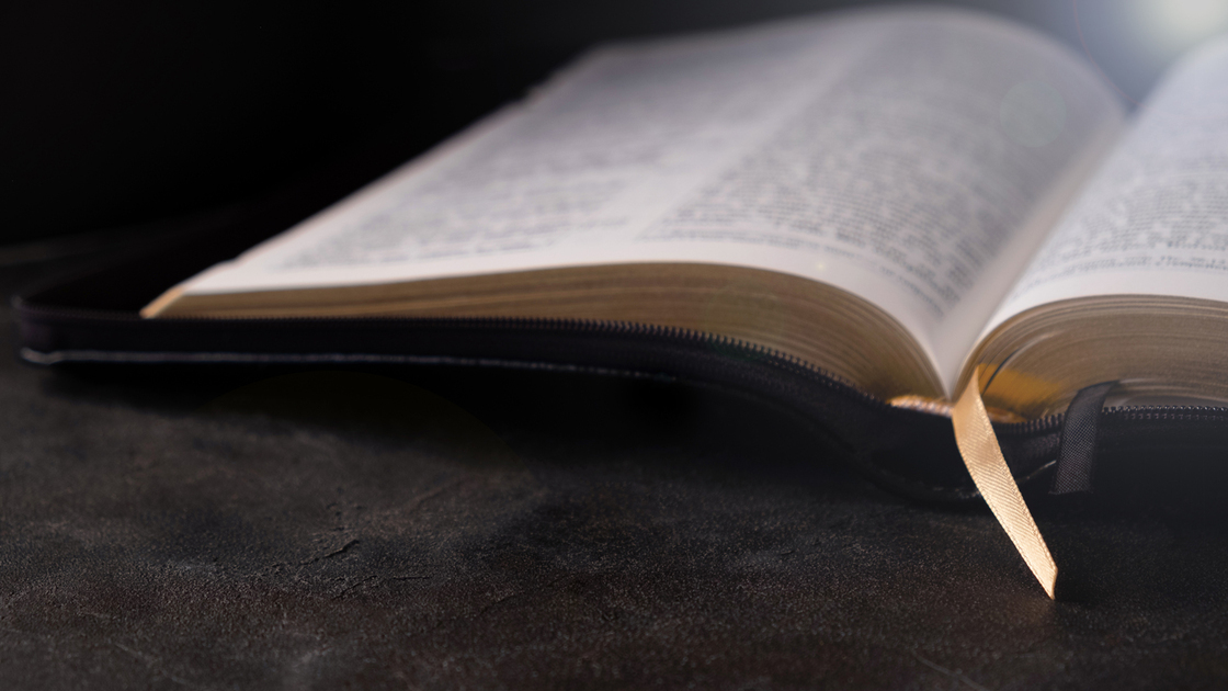 Open Bible on a dark table with light coming from above. Christianity concept. Holy Bible background.