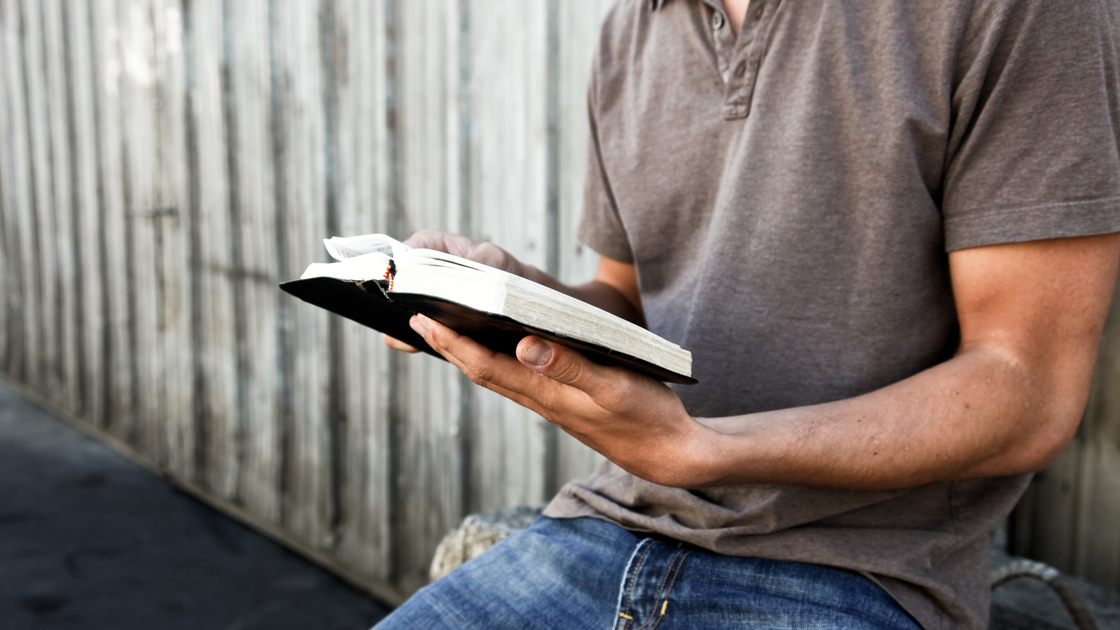 A man sitting outside and reading the Bible.