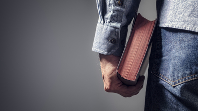 Man holding holy bible over gray background for copy concept for religion, praying, education and bible study